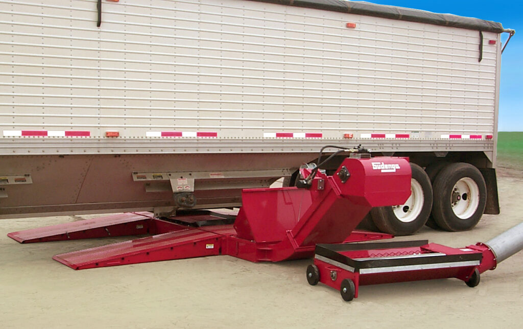 A Sudenga Portable Drive Over Hopper sits under a grain trailer, ready to unload.